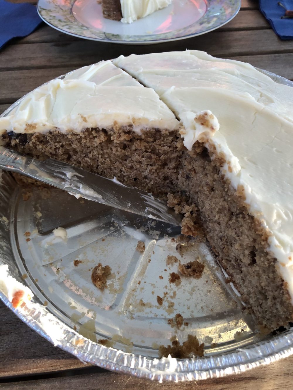 Cake with vanilla frosting in a tin cake pan. 3 pieces missing